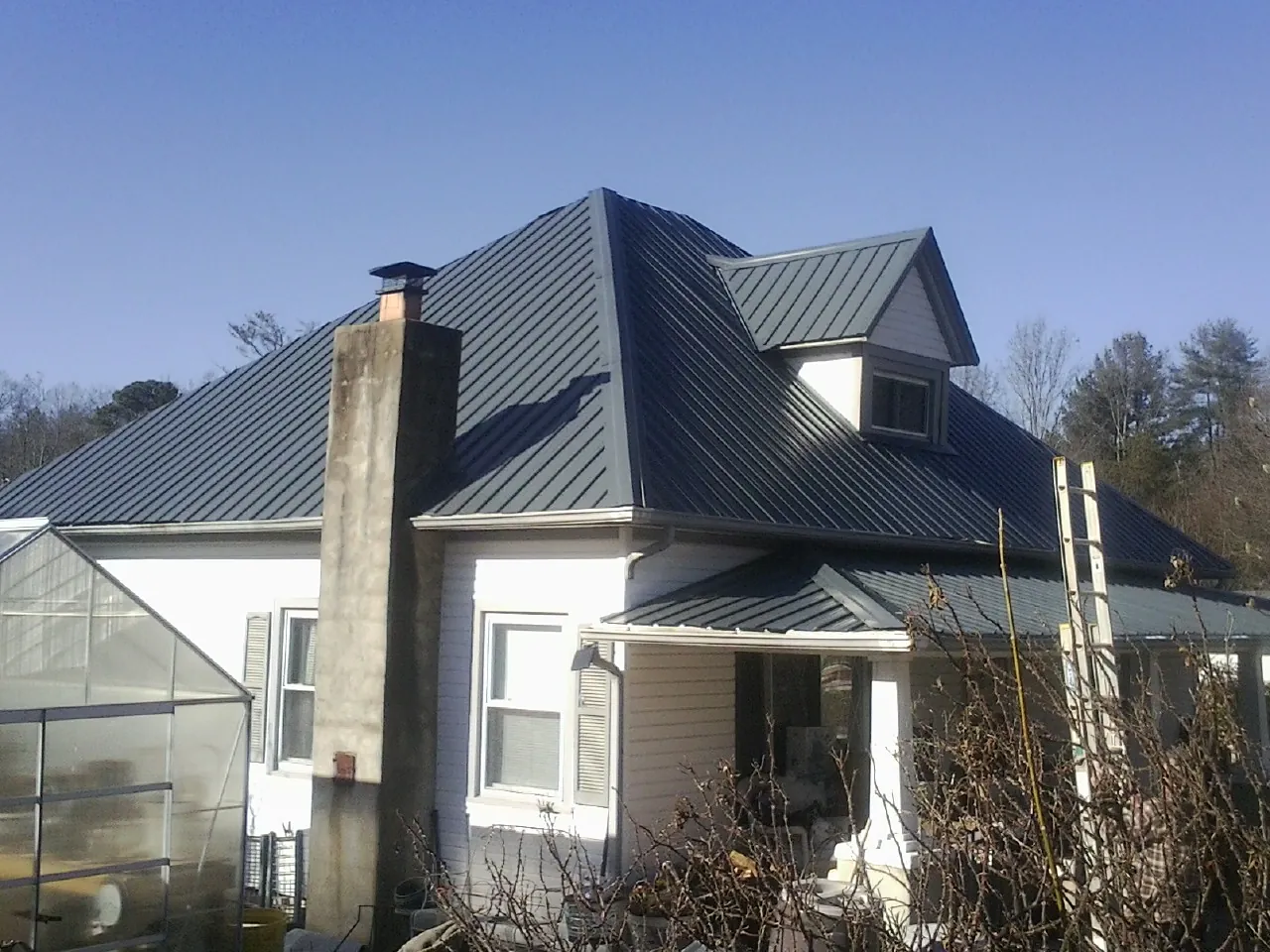 Dark blue standing seam metal roof on a white farmhouse with dormer — Slate & Tile Roof Repair by Roofing Brothers in Oak Run