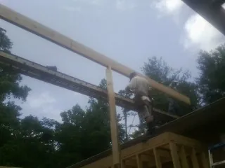 Carpenter setting a ridge beam over a new addition frame — Ice Dam Removal by Roofing Brothers in Oak Run