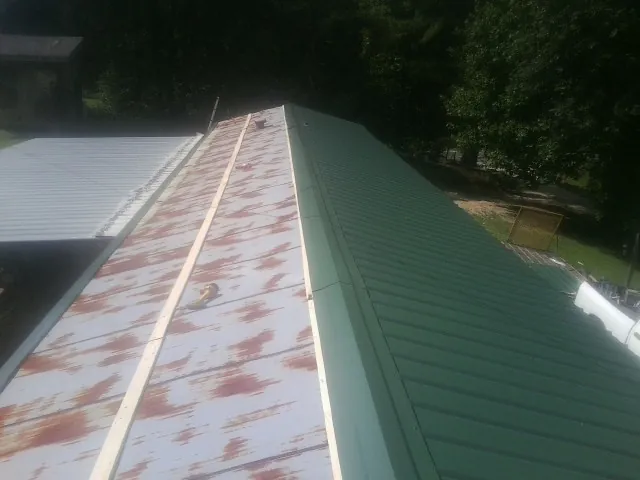 Old rusted panels beside newly installed green metal roofing — Wind Damage Roof Repair by Roofing Brothers in Oak Run