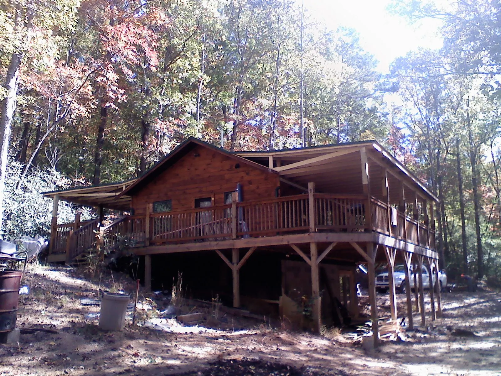 Log cabin with a wraparound porch and metal roof in the fall in Oak Run
