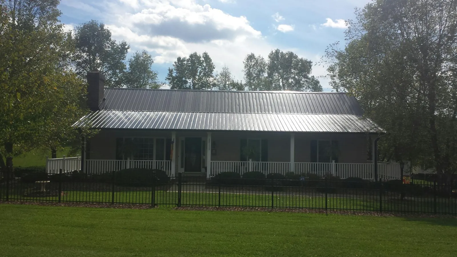 Gray metal roof on a brick ranch with a full width front porch — Gutter Guard Installation work by our crew in Oak Run