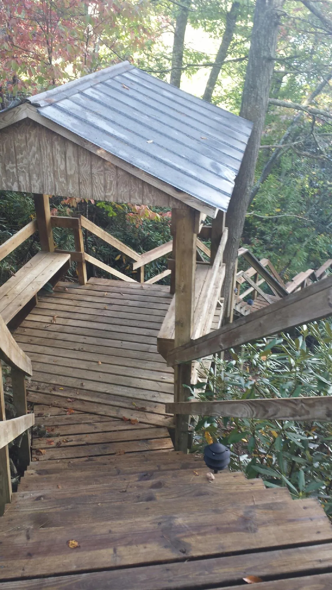 Metal roofed shelter over wooden steps on a wooded walkway — Skylight Repair & Installation work by our crew in Oak Run