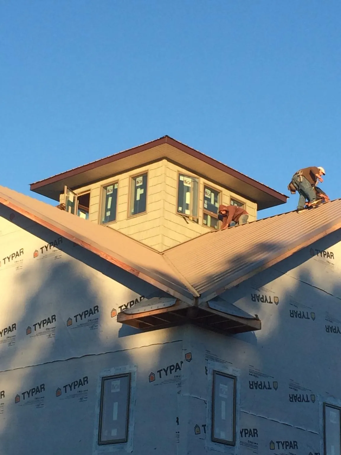 Roofers working around a rooftop cupola on a new metal roof at sunset — Roof Waterproofing in Oak Run by Roofing Brothers